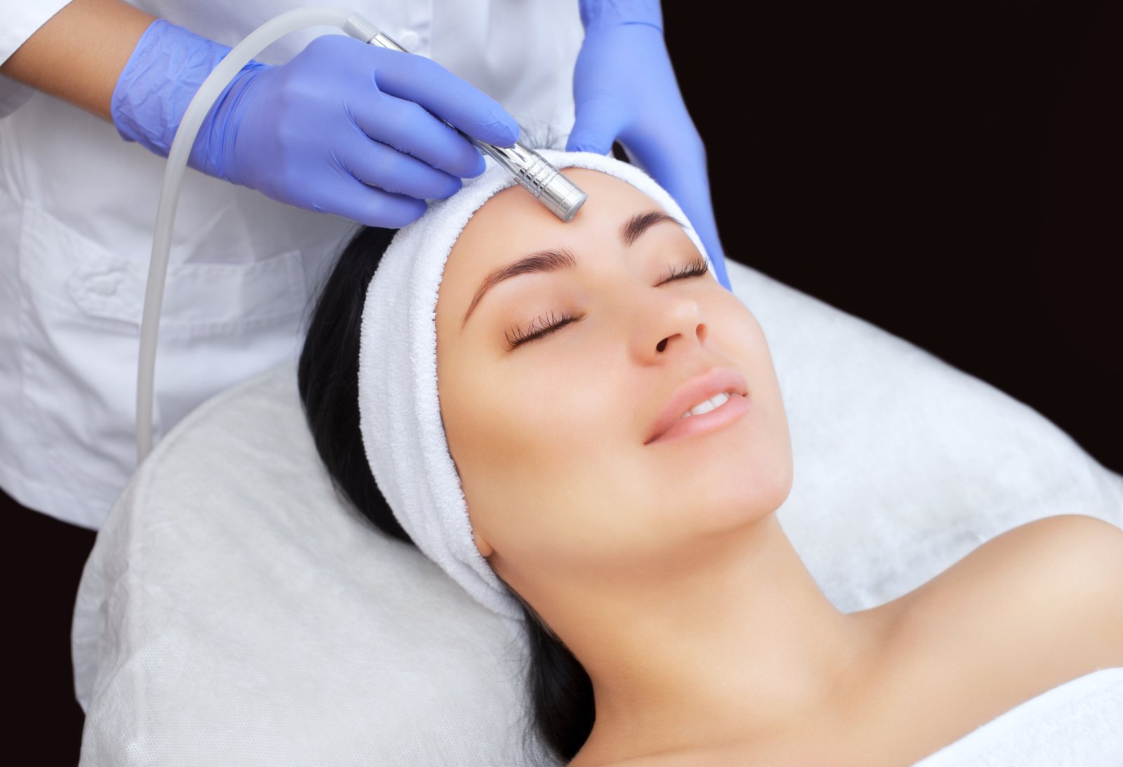 The cosmetologist makes the procedure Microdermabrasion of the facial skin